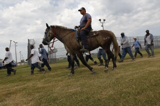 FILE - Prison guards ride horses that were broken by inmates as they return from farm work detail at the Louisiana State Penitentiary on Aug. 18, 2011, in Angola, La. Men incarcerated at Louisiana State Penitentiary filed a class-action lawsuit Saturday, Sept. 16, 2023, contending they have been forced to work in the prison’s fields for little or no pay, even when temperatures soar past 100 degrees. They described the conditions as cruel, degrading and often dangerous. (AP Photo/Gerald Herbert, File)