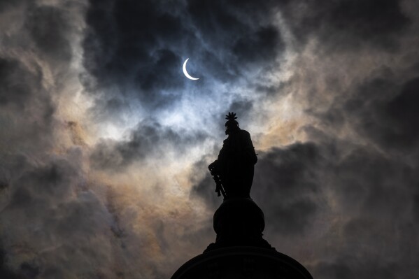 يقف تمثال الحرية فوق مبنى الكابيتول الأمريكي بينما يغطي القمر الشمس جزئيًا أثناء كسوف كلي للشمس، كما شوهد من الكابيتول هيل، الاثنين 8 أبريل 2024، في واشنطن. (صورة AP / أليكس براندون)