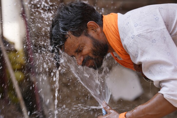 2024年5月27日，星期一，印度勒克瑙，炎热的夏日，一名男子将路边水龙头中的水泼洒在脸上，以降温。（美联社照片/拉杰什·库马尔·辛格）
