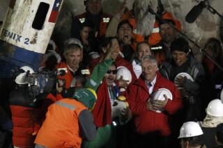 FILE - Luis Urzua, the last of the 33 miners to be rescued, center wearing green, celebrates next to Chile's President Sebastian Pinera after being pulled from the San Jose gold and copper mine near Copiapo, Chile. (AP Photo/Roberto Candia, File)
