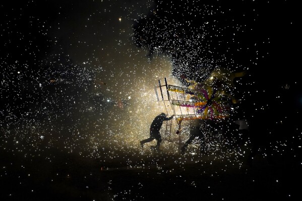 Revelers push a giant paper-mache "torito" or bull stuffed with fireworks during a nighttime lighting of bull-shaped figures as part of the annual festival honoring Saint John of God, in Tultepec, Mexico, March 8, 2024. The celebration, now its 35th year, pays homage to the patron saint of the poor and sick, St. John of God, who the fireworks' producers view as a protective figure. (AP Photo/Marco Ugarte)