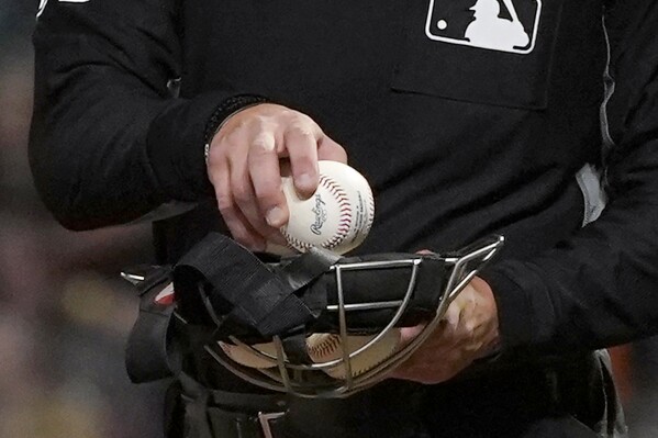 FILE - An umpire puts a ball into his face mask during a Major League Baseball game in San Francisco, Tuesday, June 15, 2021. A fired minor league umpire sued Major League Baseball, Wednesday, April 24, 2024, claiming he was sexually harassed by a female umpire and discriminated against because he is male and bisexual. (AP Photo/Jeff Chiu, File)