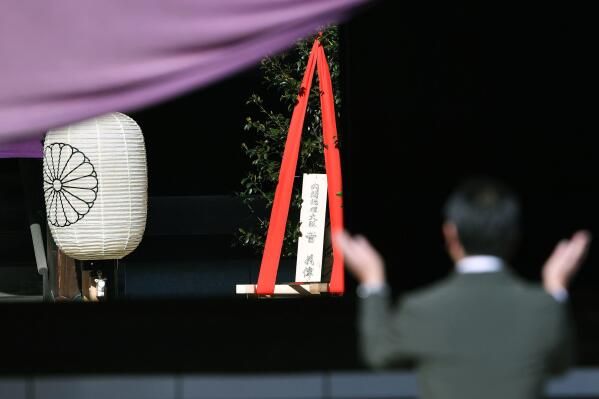A 'masakaki” tree offering, center, to Yasukuni Shrine by Japanese Prime Minister Yoshihide Suga, is placed as a man prays at the Shinto shrine in Tokyo Wednesday, April 21, 2021, the first day of the annual Spring Rites, the shrine’s biannual festival honoring the war dead, including Japanese war criminals. Suga on Wednesday donated religions offerings to the shrine viewed by China and both Koreas as a symbol of wartime aggression, though he avoided a visit.The tree's plate reads: "Prime Minister Yoshihide Suga." (Tsuyoshi Ueda/Kyodo News via AP)