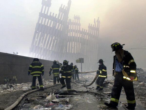 Firefighters work beneath the destroyed mullions, the vertical struts, of the World Trade Center in New York on Tuesday, Sept. 11, 2001. (AP Photo/Mark Lennihan)