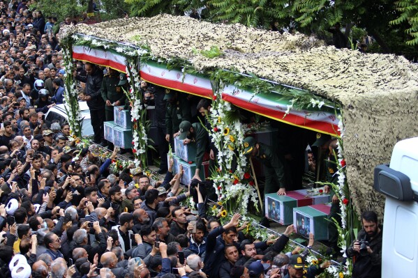 In this photo provided by Fars News Agency، mourners gather around a truck carrying coffins of Iranian President Ebrahim Raisi and his companions who were killed in their helicopter crash on Sunday in a mountainous region of the country's northwest، during a funeral ceremony at the city of Tabriz، Iran، Tuesday، May 21، 2024. Mourners in black began gathering Tuesday for days of funerals and processions for Iran's late president، foreign minister and others killed in a helicopter crash، a government-led series of ceremonies aimed at both honoring the dead and projecting strength in an unsettled Middle East. (Ata Dadashi، Fars News Agency via AP)