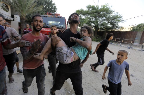 FILE - Palestinians carry a wounded girl after being rescued from under the rubble of buildings that were destroyed by Israeli airstrikes in Jabaliya refugee camp, northern Gaza Strip, Nov. 1, 2023. The White House says Israel has agreed to put in place four-hour daily humanitarian pauses in its assault on Hamas in northern Gaza (AP Photo/Abed Khaled, File)