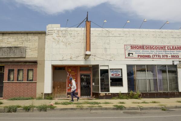A man walks past one of the many closed businesses along East 79th Street in Chicago on Friday, Aug. 13, 2021, in a neighborhood on the South Side near where the shooting of Safarian Herring took place in May 2020. (AP Photo/Mark Black)