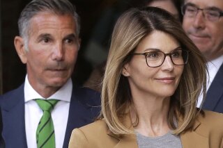 FILE - In this April 3, 2019, file photo, actress Lori Loughlin, front, and her husband, clothing designer Mossimo Giannulli, left, depart federal court in Boston. "Full House" actress Loughlin, Giannulli and other prominent parents told a judge Wednesday, March 25, 2020, that he should dismiss charges against them in the college admissions bribery case, accusing prosecutors of "extraordinary" misconduct. (AP Photo/Steven Senne, File)