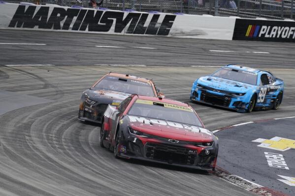 Ross Chastain (1) leads Kevin Harvick (4) and Daniel Suarez (99) out of Turn 4 during a NASCAR Cup Series auto race at Martinsville Speedway, Sunday, Oct. 30, 2022, in Martinsville, Va. (AP Photo/Chuck Burton)