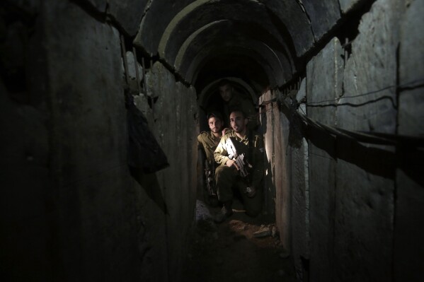 FILE - Israeli soldiers walk through a tunnel discovered near the Israel-Gaza border Sunday, Oct. 13, 2013. An extensive labyrinth of tunnels built by Hamas stretches across the dense neighborhoods of the Gaza Strip, hiding militants, their missile arsenal and the over 200 hostages they now hold after an unprecedented Oct. 7, 2023, attack on Israel. (AP Photo/Tsafrir Abayov, File)