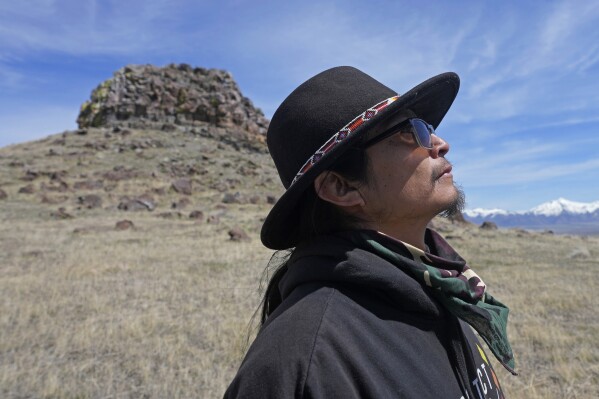 FILE - Gary McKinney, a spokesman for People of Red Mountain and a member of the nearby Duck Valley Shoshone-Paiute Tribe, walks near Sentinel Rock on April 25, 2023, outside of Orovada, Nev. The Reno-Sparks Indian Colony is abandoning its 3-year lawsuit aimed at blocking a lithium mine currently under construction at Thacker Pass in northwest Nevada. Tribal leaders say the U.S. Interior Department refuses to accept their arguments that the mine's on a sacred site where more than two dozen Paiute and Shoshone ancestors were massacred in 1865. (AP Photo/Rick Bowmer, File)