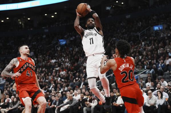 Brooklyn Nets guard Kyrie Irving (11) scores over Toronto Raptors guard Jeff Dowtin Jr. (20) as Raptors forward Juancho Hernangomez (41) watches during the second half of an NBA basketball game Wednesday, Nov. 23, 2022, in Toronto. (Chris Young/The Canadian Press via AP)