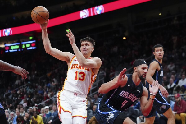 Atlanta Hawks guard Bogdan Bogdanovic (13) passes as he drives against Orlando Magic guard Jalen Suggs (4) during the first half of an NBA basketball game Wednesday, Jan. 17, 2024, in Atlanta. (AP Photo/John Bazemore)