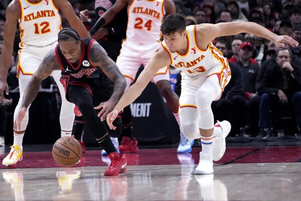 Chicago Bulls forward DeMar DeRozan, left, and Atlanta Hawks guard Bogdan Bogdanovic reach for the ball during the first half of an NBA basketball play-in tournament game in Chicago, Wednesday, April 17, 2024. (AP Photo/Nam Y. Huh)