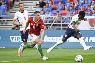 Hungary's Willi Orban, center, in action against England's Bukayo Sak, right, during the UEFA Nations League soccer match between Hungary and England at the Puskas Arena in Budapest, Hungary, Saturday, June 4, 2022. (Zsolt Szigetvary/MTI via AP)