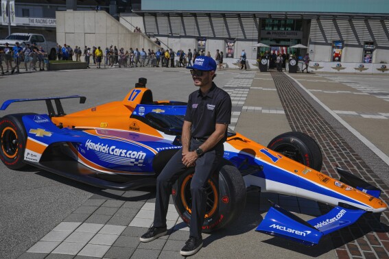 FILE - Kyle Larson sits on the car that he will drive in the IndyCar Indianapolis 500 after is was unveiled at Indianapolis Motor Speedway in Indianapolis, Sunday, Aug. 13, 2023. Larson next month will become the fifth driver in history to attempt to complete “The Double” and run 1,100 miles in one day at both the Indianapolis 500 in an Indy car and the Coca-Cola 600, NASCAR's longest race of the year. (AP Photo/Michael Conroy, File)