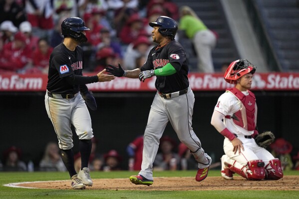 Cleveland Guardians' Jose Ramirez, center, is congratulated by Andres Gimenez, left, after hitting a two-run home run as Los Angeles Angels catcher Logan O'Hoppe kneels at the plate during the fourth inning of a baseball game Friday, May 24, 2024, in Anaheim, Calif. (AP Photo/Mark J. Terrill)
