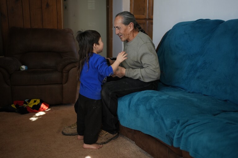 Blas Sanchez talks with his step grandson, Mauricio, at a motel he owns and operates, Friday, Jan. 26, 2024, in Winslow, Ariz. Sanchez's right leg was mutilated while working near the chicken manure chute as a prison laborer at Hickman's Family Farms in 2015 in Tonopah, Ariz. (AP Photo/John Locher)