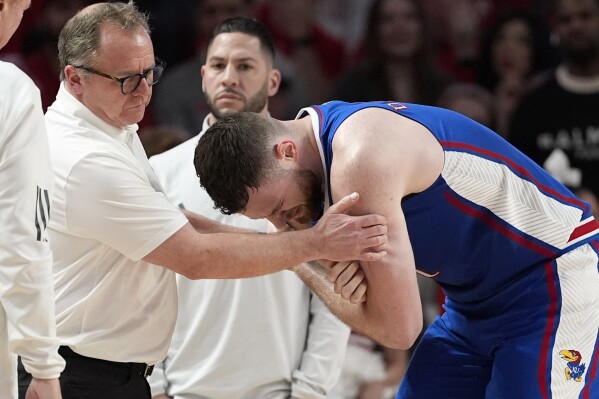 Kansas's Hunter Dickinson, right, is helped after being injured during the second half of an NCAA college basketball game against Houston Saturday, March 9, 2024, in Houston. Houston won 76-46. (AP Photo/David J. Phillip)