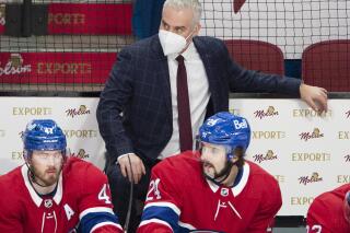 FILE - Montreal Canadiens coach Dominique Ducharme keeps an eye on the action, as do Paul Byron (41) and Phillip Danault (24) during the the team's NHL hockey game against the Ottawa Senators in Montreal, in this Tuesday, March 2, 2021, file photo. The four coaches left in the NHL playoffs have connections to each other, but they all took different paths to get to this point. (Ryan Remiorz/The Canadian Press via AP)