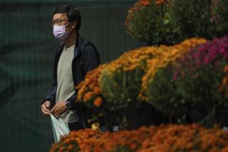 A person wears a mask while walking past a flower display in front of a supermarket on Front Street East in Toronto on Friday, Sept. 16, 2022. (Alex Lupul /The Canadian Press via AP)