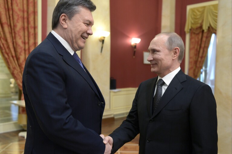 FILE - Russian President Vladimir Putin, right, shakes hands with Ukrainian President Viktor Yanukovych at an Olympic reception in Sochi, Russia on Friday, Feb. 7, 2014. Despite the costly effort by the Kremlin to make the Sochi Games a symbol of Russia's power and prestige, global attention soon focused on clashes between police and protesters who rallied against Ukraine's Moscow-backed president in the streets of Kyiv. (Alexei Nikolsky, Sputnik, Kremlin Pool Photo via AP, File)