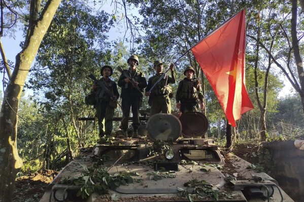 Members of the Myanmar National Democratic Alliance Army hold the group's flag as they pose for a photograph on a captured army armored vehicle in Myanmar, Saturday Oct. 28, 2023. The leader of Myanmar’s army-installed government said the military will carry out counter-attacks against a powerful alliance of ethnic armed groups that has seized towns near the Chinese border in the country’s northeastern and northern regions, state-run media reported Friday Nov. 3, 2023. (