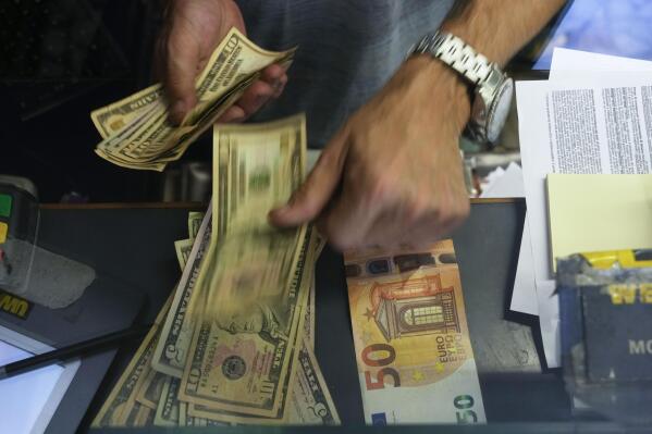 A cashier changes a 50 Euro banknote with US dollars at an exchange counter in Rome, Wednesday, July 13, 2022. The euro on Tuesday fell to parity with the dollar for the first time in nearly 20 years. (AP Photo/Gregorio Borgia)