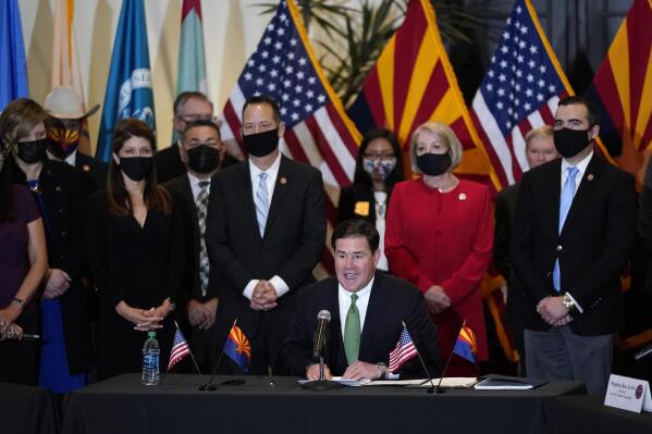 Surrounded by Arizona legislators, Republican Arizona Gov. Doug Ducey speaks at a bill signing allowing a major expansion of sports betting in Arizona at an event at the Heard Museum Thursday, April 15, 2021, in Phoenix. The measure approved by the Legislature adds additional types of table games at tribal casinos and for the first time allows sports betting under licenses issued to tribes and pro sports teams. (AP Photo/Ross D. Franklin)