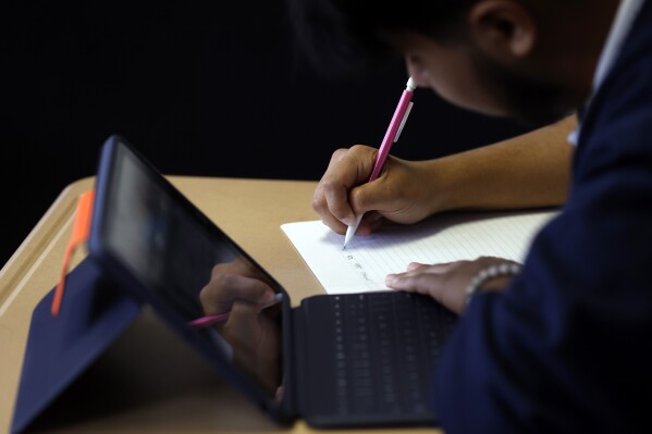 Audiel Miranda Cambron takes notes as he prepares for the digital SAT, Wednesday, March 6, 2024, at Holy Family Cristo Rey Catholic High School in Birmingham, Ala. (AP Photo/Butch Dill)