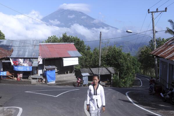 A Balinese woman walks toward a temple as Mount Agung volcano covered with clouds seen in the background at a village in Karangasem, Bali, Indonesia, Tuesday, Sept. 26, 2017. An increasing frequency of tremors from the volcano indicates magma is continuing to move toward the surface and an eruption is possible, a disaster agency official said Tuesday. Tourists are cutting short their stay to the island, where an eruption would force the airport to close and strand thousands. (AP Photo/Firdia Lisnawati)