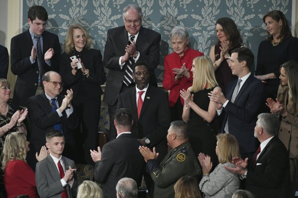 In this Feb. 4, 2020, photo, Tony Rankins, center in red tie, receives a standing ovation during the State of the Union address to a joint session of Congress on Capitol Hill in Washington. Rankins, a formerly homeless, drug-addicted Army vet, got the standing ovation after President Donald Trump described how he turned his life around thanks to a construction job at a company using the administration’s “Opportunity Zone” tax breaks targeting poor neighborhoods. Rankins, a tradesman who has indeed moved out of his car and into an apartment since landing the job refurbishing a Nashville hotel two years ago, doesn’t work at a site using the tax breaks and never has. (AP Photo/Susan Walsh)