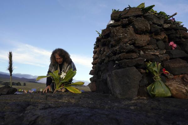 Illona Ilae, a Native Hawaiian from Kailua-Kona, Hawaii, leaves an offering in front an alter below the Mauna Loa volcano as it erupts Thursday, Dec. 1, 2022, near Hilo, Hawaii. Glowing lava from the world's largest volcano is a sight to behold, but for many Native Hawaiians, Mauna Loa's eruption is a time to pray, make offerings and honor both the natural and spiritual worlds. (AP Photo/Gregory Bull)