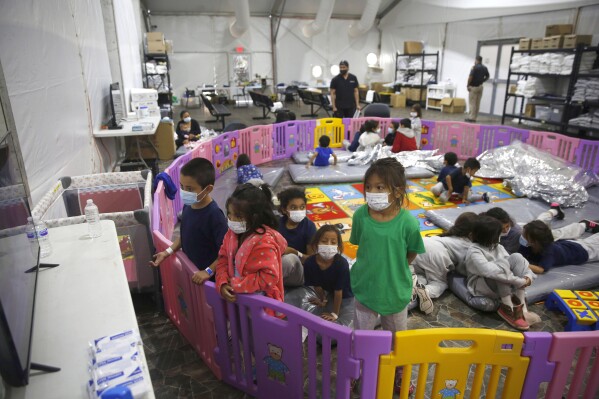 In this March 30, 2021, file photo, young unaccompanied migrants, watch television inside a playpen at the U.S. Customs and Border Protection facility, the main detention center for unaccompanied children in the Rio Grande Valley, in Donna, Texas. (AP Photo/Dario Lopez-Mills, Pool, File)