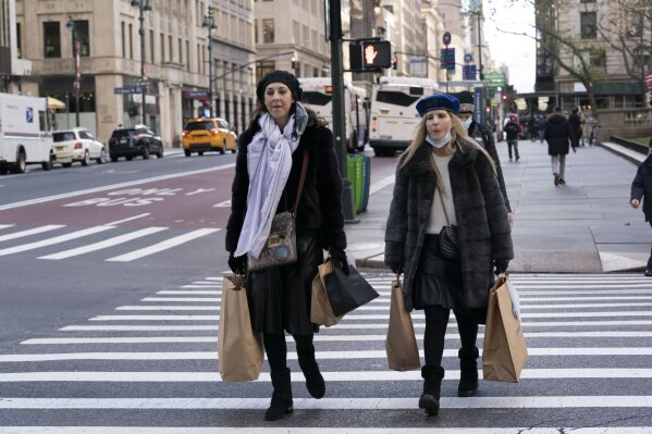 FILE - Women carry shopping bags, Thursday, Dec. 10, 2020, in New York.   Shoppers, who can't touch or feel products they're ordering,  are expected to return items during the holiday season at a rate double from last year, costing retailers roughly $1.1 billion, according to Narvar Inc.,  a software and technology company that manages online returns for hundreds of brands.  That puts retailers in a conundrum: they don't want the returns, but they also want to make shoppers feel comfortable to freely buy without worry. (AP Photo/Mark Lennihan)