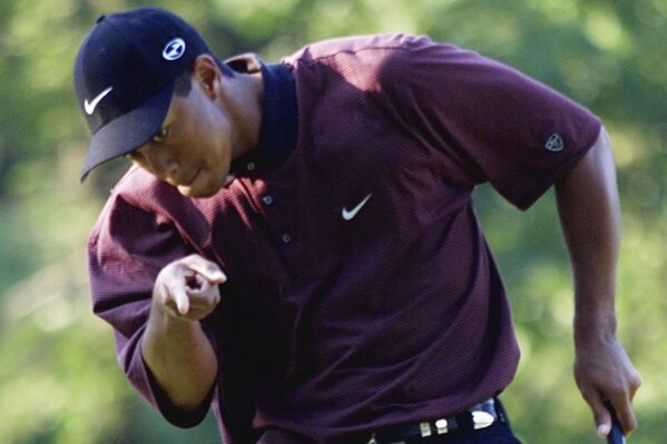 Tiger Woods points to his ball as it drops for birdie on the first hole of a three-hole playoff against Bob May at the PGA Championship, Sunday, Aug. 20, 2000, at the Valhalla Golf Club in Louisville, Ky. May mad par on the hole. (AP Photo/Chuck Burton, File)