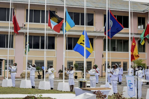 Members of the Trinidad and Tobago Defence Force raise the flags of CARICOM nations during a flag raising ceremony at the Convention Centre in Chaguaramas, Trinidad and Tobago, Tuesday, July 4, 2023. Tuesday marks the 50th Anniversary of the signing of the Treaty of Chaguaramas, which established the Caribbean Community, CARICOM. (AP Photo/Curtis Chase)