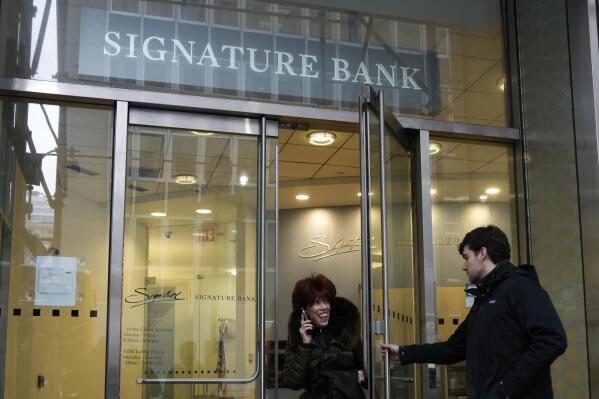 FILE - A woman leaves a branch of Signature Bank in New York, Monday, March 13, 2023. New York Community Bank has agreed to buy a significant chunk of the failed Signature Bank in a $2.7 billion deal, the Federal Deposit Insurance Corp., said late Sunday, March 19, 2023. (AP Photo/Seth Wenig, File)