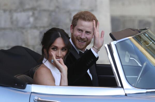 FILE - In this Saturday, May 19, 2018 file photo the newly married Duke and Duchess of Sussex, Meghan Markle and Prince Harry, leave Windsor Castle in a convertible car after their wedding in Windsor, England, to attend an evening reception at Frogmore House, hosted by the Prince of Wales. Prince Harry and Meghan Markle are to no longer use their HRH titles and will repay £2.4 million of taxpayer's money spent on renovating their Berkshire home, Buckingham Palace announced Saturday, Jan. 18. 2020. (Steve Parsons/pool photo via AP, File)