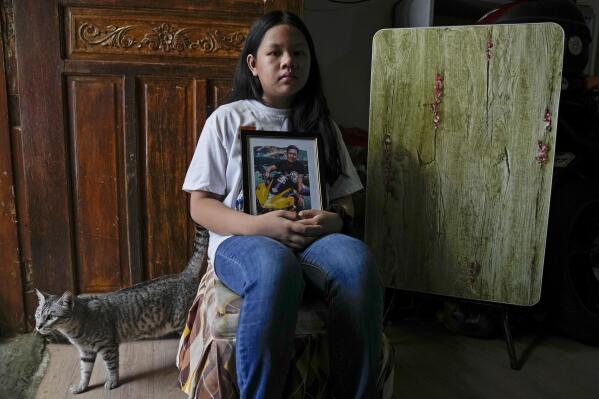 Yael Navales poses at home in Quezon city, Philippines, on Tuesday July 6, 2021, with an image of her father, Arthur, who died from the coronavirus. "Our house became quiet and sad. We don't laugh much since papa left," she said. (AP Photo/Aaron Favila)