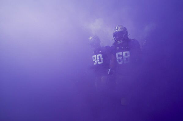 Washington defensive lineman Elinneus Davis (90) and offensive lineman Soane Faasolo (68) walk out through purple smoke before the team's NCAA college football game against Boise State, Saturday, Sept. 2, 2023, in Seattle. (AP Photo/Lindsey Wasson)