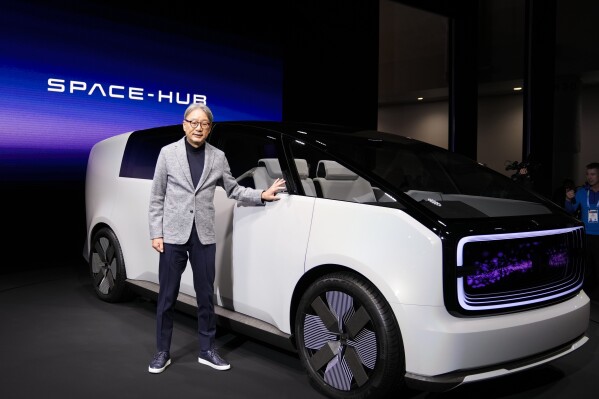 Toshihiro Mibe, director, president and representative executive officer, Honda Motor Co., poses next to the newly unveiled concept car, the Honda Zero Series "Space-Hub" electric vehicle during a Honda news conference during the CES tech show Tuesday, Jan. 9, 2024, in Las Vegas. (AP Photo/Ryan Sun)