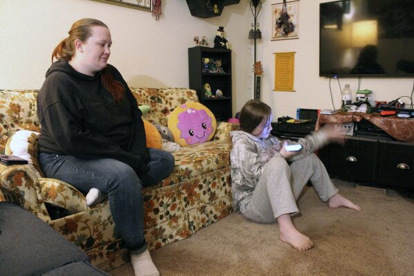 Taylor Wood sits next to her 10-year-old daughter, Freya Wood, in their Corvallis, Ore., apartment on Dec. 11, 2020. The family has missed three months of rent payments during the pandemic and faces eviction if a moratorium is not extended. (AP Photo/Sara Cline)