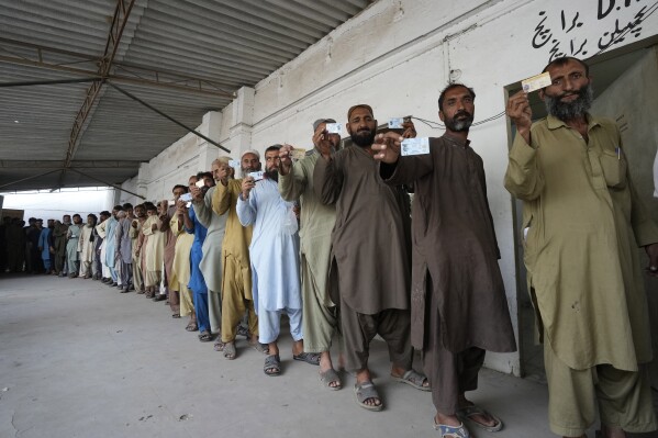 Immigrants, mostly Afghans, show their ID cards as they wait their turn to verify data at a counter of Pakistan's National Database and Registration Authority, in Karachi, Pakistan, Tuesday, Nov. 7, 2023. Pakistan government launched a crackdown on migrants living in the country illegally as a part of the new measure which mainly target all undocumented or unregistered foreigners. (AP Photo/Fareed Khan)