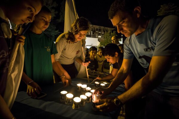 
              Israelis light candles in the Israeli settlement of Halamish, Saturday, July 22, 2017. Israel's military has sent more troops to the West Bank and placed forces on high alert a day after a Palestinian stabbed to death three members of an Israeli family and Israeli-Palestinian clashes erupted over tensions at the Holy Land's most contested shrine. (AP Photo/Tsafrir Abayov)
            