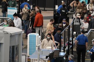FILE - In this Thursday, Feb. 18, 2021, file photo, travelers wear face coverings as they queue up at the north security checkpoint in the main terminal of Denver International Airport, in Denver. ...
