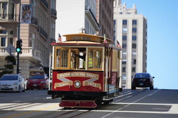 A cable car dedicated to Tony Bennett makes its way up California Street to Nob Hill in San Francisco, Thursday, March 14, 2024. Tony Bennett loved San Francisco and its cable cars and in return, the city has dedicated one of those cable cars to the famous crooner who died in July. Cable car 53, built in 1907, has several plaques and painted gold ribbons remembering Bennett. (AP Photo/Eric Risberg)