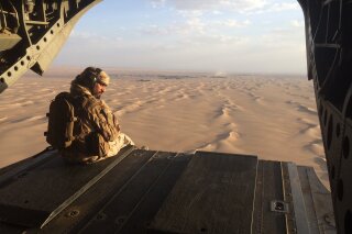 FILE - In this Sept. 17, 2015 photo, an Emirati gunner watches for enemy fire from the rear gate of a United Arab Emirates Chinook military helicopter flying over Yemen. Six Emirati troops have been killed in a "collision," the United Arab Emirates said Friday, Sept. 13, 2019, without elaborating nor offering a location for the incident that comes after the federation of sheikhdoms began pulling out of a Saudi-led war in Yemen. Yemeni officials speaking to The Associated Press said the troops were killed in a road crash in southern Yemen. (AP Photo/Adam Schreck, File)