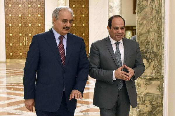 FILE - In this May 9, 2019 file photo, provided by Egypt's presidency media office, Egyptian President Abdel-Fattah el-Sissi, right, walks with military commander Khalifa Hifter, the head of the self-styled Libyan National Army, in Cairo, Egypt. The Egyptian Parliament is likely to vote Monday, July 20, 2020, to authorize the country's president to deploy troops to war-torn Libya if Turkey-backed forces allied with the U.N.-supported government in Tripoli move to retake the strategic coastal city of Sirte. The country is now split between a government in the east, allied with Hifter, and one in Tripoli, in the west, supported by the United Nations. Along with Egypt, Hifter is also backed by the United Arab Emirates and Russia, while the in addition to Turkey, the Tripoli forces are aided by Qatar and Italy. (Egyptian Presidency Media office via AP, File)