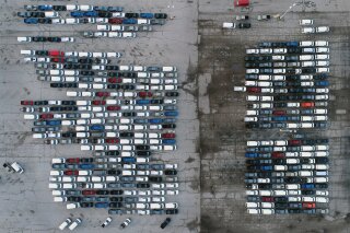 In this aerial photo, mid-sized pickup trucks and full-size vans are seen in a parking lot outside a General Motors assembly plant where they are produced Wednesday, March 24, 2021, in Wentzville, ...